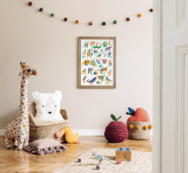 Framed children's animal alphabet poster with animal illustrations on a wall in a nursery.
