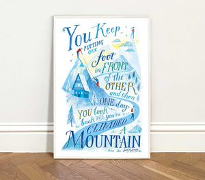 Framed motivational poster with mountain illustration and text on a white wall.
