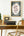 Desk with typewriter, framed poster of Name of the Wind by Patrick Rothfuss book cover, and decorative items in a room setting
