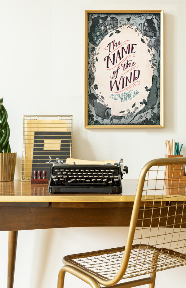 Desk with typewriter, framed poster of Name of the Wind by Patrick Rothfuss book cover, and decorative items in a room setting
