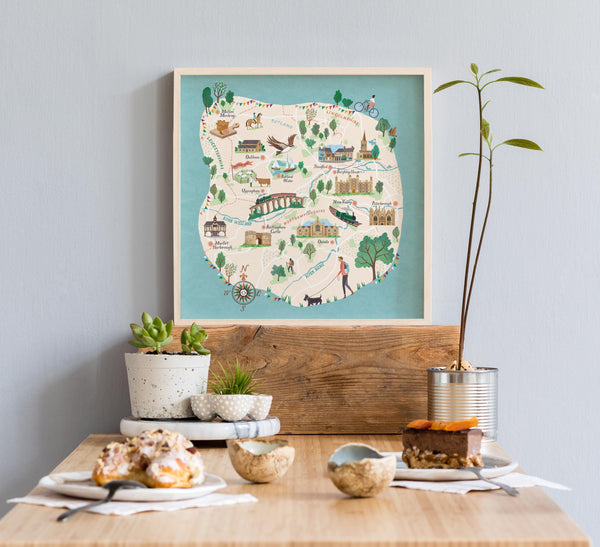 Decorative Stamford map on a wall above a table with food and plants. Key landmarks are Rutland, Market Harborough, Uppingham, Oundle, Nene Valley, Melton Mowbray and Oakham
