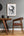 Wooden table and chair in a room with a framed black and white artwork of 'The Night Circus' on the wall.
