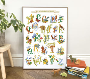 Framed children's Woodland alphabet poster on a wall with animals, plants and flower illustrations. 