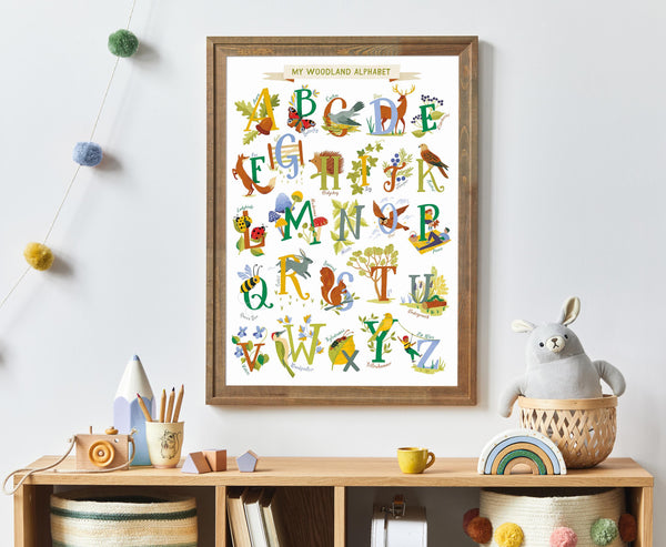 Framed children's woodland alphabet poster on a wall with toys and decor below.