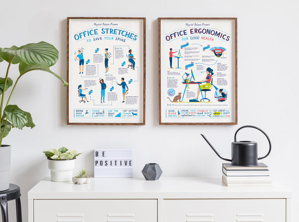 Two framed posters on a wall with office stretches and ergonomics information, next to a plant and books.
